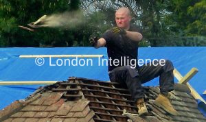 A 21st Century roofer sheds tiles from a mid-20th Century north London suburban bungalow © Paul Coleman, London Intelligence ®